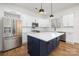 Modern kitchen featuring stainless steel appliances, white cabinets, and a contrasting dark blue island with a white countertop at 302 Lincoln St, Belmont, NC 28012