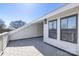 White outdoor deck with a fence, grey floor, light, windows, and some trees in the background at 3115 Pinehurst Pl, Charlotte, NC 28209