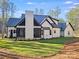 Exterior rear view of a white farmhouse with a screened porch overlooking a lush green lawn and mature trees at 4354 Persimmon Rd, Lancaster, SC 29720