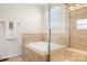 Bright bathroom featuring a soaking tub, tile surround, and a glass-enclosed shower with natural light at 7217 Kenyon Dr, Denver, NC 28037