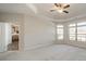 Spacious bedroom featuring plush carpet, tray ceilings, a ceiling fan, and large windows at 1005 Headwaters Ct, Matthews, NC 28104