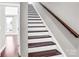 Staircase with hardwood steps and white risers, complemented by a dark wood handrail and neutral wall color at 111 W Poindexter Dr, Charlotte, NC 28203