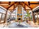 Spacious living room featuring exposed timber beams, a stone fireplace, grand piano, and large windows at 12613 Oak Grove Rd, Stanfield, NC 28163