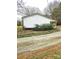 The side of the house, with a strip of bushes, dirt, and a gravel drive at 1607 W Nc 27 Hwy, Lincolnton, NC 28092
