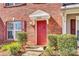 Close-up of the red front door and manicured landscaping of the charming townhouse at 19009 Coachmans Trce, Cornelius, NC 28031