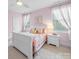 A sunny pink bedroom with a large window and a white bed frame at 3024 Beaver Dam Dr, Monroe, NC 28110
