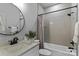 Bright bathroom featuring a white vanity, round mirror, and shower-tub combo with gray subway tile surround at 3328 Flamingo Ave, Charlotte, NC 28205