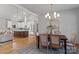 Elegant dining area adjacent to the kitchen, featuring a wooden table, modern chandelier, and hardwood floors at 3328 Flamingo Ave, Charlotte, NC 28205
