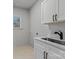 Well-lit laundry room features white cabinets and countertops with a stainless steel sink at 3328 Flamingo Ave, Charlotte, NC 28205