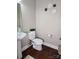 Well-lit half bathroom featuring a stylish pedestal sink, modern toilet with plant, and unique floral wall decor at 3500 Exbury Gardens Dr, Waxhaw, NC 28173