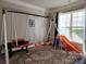 Bright playroom with a large window, carpet, and an indoor swing set with slide for hours of fun at 3500 Exbury Gardens Dr, Waxhaw, NC 28173