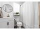Updated bathroom with modern vanity, round mirror, and shower with white shower curtain at 5616 Ebley Ln, Charlotte, NC 28227