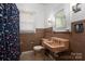 A peach-toned vintage bathroom features a floral shower curtain, tiled walls, and a window at 634 Carolina Ave, Gastonia, NC 28052