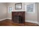 A close-up shot of the brick fireplace, flanked by windows, and with beautiful floors at 634 Carolina Ave, Gastonia, NC 28052