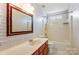 Well-lit bathroom featuring a large mirror, a single vanity, and a shower-tub combo with a window at 7815 Ambleside Dr, Charlotte, NC 28216