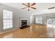 Bright living room boasts a fireplace, wood floors, a ceiling fan and plenty of natural light from large windows at 7815 Ambleside Dr, Charlotte, NC 28216