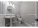 Charming powder room with classic pedestal sink, toilet, and neutral color scheme at 10101 Woodview Cir, Charlotte, NC 28277