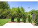 Landscaped backyard with a lush lawn, privacy trees, and a black metal fence at 104 Kentmore Dr, Waxhaw, NC 28173