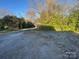 Large gravel parking area next to yard with mature trees and lush greenery at 107 N Market St, Lancaster, SC 29720