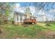 View of backyard with a wooden deck, chimney and a green lawn surrounded by a wooden fence at 11404 Larix Dr, Charlotte, NC 28273