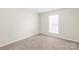 A bright bedroom offers a neutral color palette, carpet floors, and a large window for natural light at 11404 Larix Dr, Charlotte, NC 28273