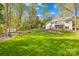 Large backyard with a lush lawn, mature trees, stone retaining wall, and fenced perimeter at 12228 Plover Dr, Charlotte, NC 28269