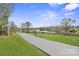 Scenic driveway leading to the property, lined with green grass, a pond, and mature trees at 1620 London Rd, Mooresville, NC 28115