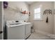 Well-lit laundry room with a front-loading washer and dryer, storage shelves, and a window at 17436 Langston Dr, Charlotte, NC 28278