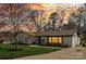 Charming single-story home featuring a well-manicured lawn and neutral paint with mature trees, enhanced by a vibrant sunset at 2052 10Th Street Nw Pl, Hickory, NC 28601