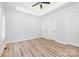 A spacious, bright bedroom featuring a tray ceiling, a ceiling fan, and wood flooring at 402 Walker St, Kannapolis, NC 28081