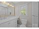 Well-lit bathroom featuring a vanity with drawers, subway tile walls, and a decorative mirror at 6117 Brace Rd, Charlotte, NC 28211