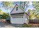 View of the detached garage with white door and gray siding, and boat parked to the side at 6117 Brace Rd, Charlotte, NC 28211