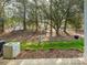 Scenic backyard with trees, partial patio, and an external AC unit adjacent to the covered portion of the patio at 9427 S Vicksburg Park Ct, Charlotte, NC 28210