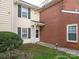Exterior view of cream and brick townhome with manicured lawn, shrubs, and storm door at 9427 S Vicksburg Park Ct, Charlotte, NC 28210