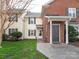 Exterior view of cream and brick townhome with manicured lawn, shrubs, and storm door at 9427 S Vicksburg Park Ct, Charlotte, NC 28210