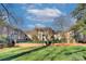 Brick apartment building with mature trees, landscaped lawn, and an iron fence in front at 101 S Laurel Ave # 72A, Charlotte, NC 28207