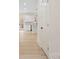 Hallway leading to a modern kitchen with an island, white cabinetry, and light wood floors at 10405 Briarhurst Pl # 18, Mint Hill, NC 28227