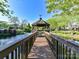 Picturesque view of a gazebo on a pond, accessible by a wooden bridge, surrounded by lush landscaping at 11406 Olde Turnbury Ct, Charlotte, NC 28277