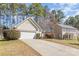 Inviting home featuring a two-car garage, a well-maintained lawn, and a lengthy driveway set against a backdrop of mature trees at 12810 English Walnut Ln, Charlotte, NC 28215