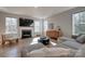 Sunlit living room with fireplace, large windows, hardwood floors, and stylish neutral-toned furniture at 15606 Walnut Hill Dr, Charlotte, NC 28278