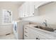 Bright laundry room featuring a washer and dryer, a stainless steel sink, and white cabinets for ample storage space at 1730 Townsend Ln, Rock Hill, SC 29730