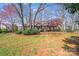View of a Tudor-style home surrounded by mature trees and landscaping, offering a serene setting at 2324 Chestnut Ln, Matthews, NC 28104