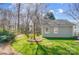 Grassy backyard with tree, mulch and a side view of the home with two windows and a garden at 3842 Saxonbury Way, Charlotte, NC 28269