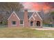 Charming brick home featuring gabled roof lines and an arched entryway, surrounded by a well-maintained lawn at 410 E Arch St, Lancaster, SC 29720