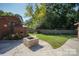 A backyard featuring a fire pit, green grass, privacy fence, and the exterior of the brick home at 4824 Harcourt Ln, Charlotte, NC 28212