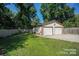 A two-car garage, with an adjacent green lawn and privacy fence, in this property's backyard at 4824 Harcourt Ln, Charlotte, NC 28212