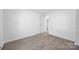 Bright bedroom featuring wood-look flooring, fresh paint, and a door leading to an adjacent room at 5015 Forestmont Dr, Matthews, NC 28105