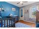 Bedroom with hardwood floors, blue accent wall, ceiling fan, window, crib and dresser with changing table at 5230 Northview Dr, Hickory, NC 28601