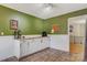 Bright kitchen and adjoining hallway with wainscotting, featuring white cabinetry, butcher block countertops and dark green accent wall at 5230 Northview Dr, Hickory, NC 28601