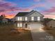 Charming two-story home with a covered porch and a two-car garage, showcasing its inviting curb appeal at 603 Smokehouse Ln, Albemarle, NC 28001